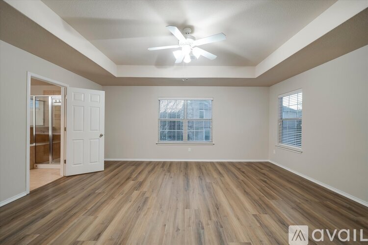 A spacious room with wooden flooring and a ceiling fan.