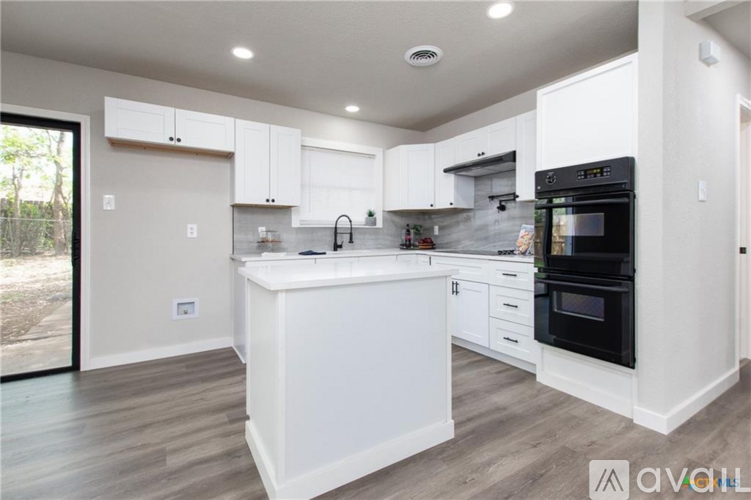 A modern kitchen with white cabinets and a black oven.