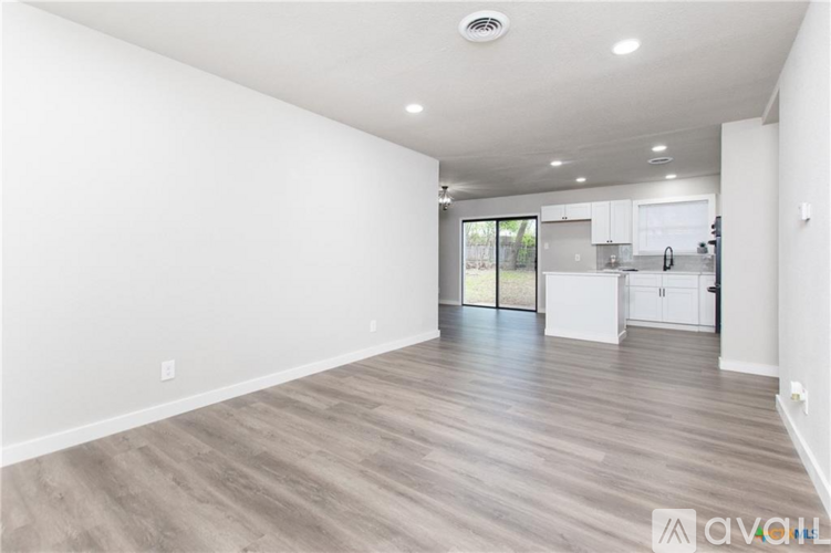 A spacious room with wooden flooring and white walls.