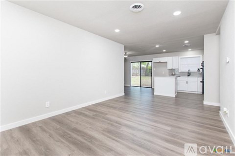 A spacious room with wooden flooring and white walls.