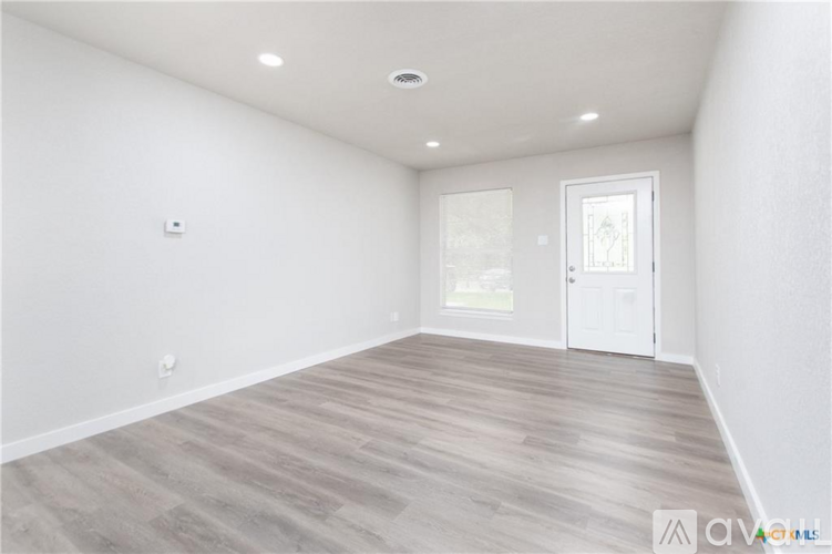 A spacious room with wooden flooring and a white door.