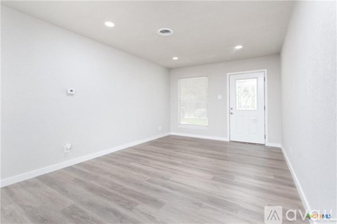 A spacious room with wooden flooring and a white door.