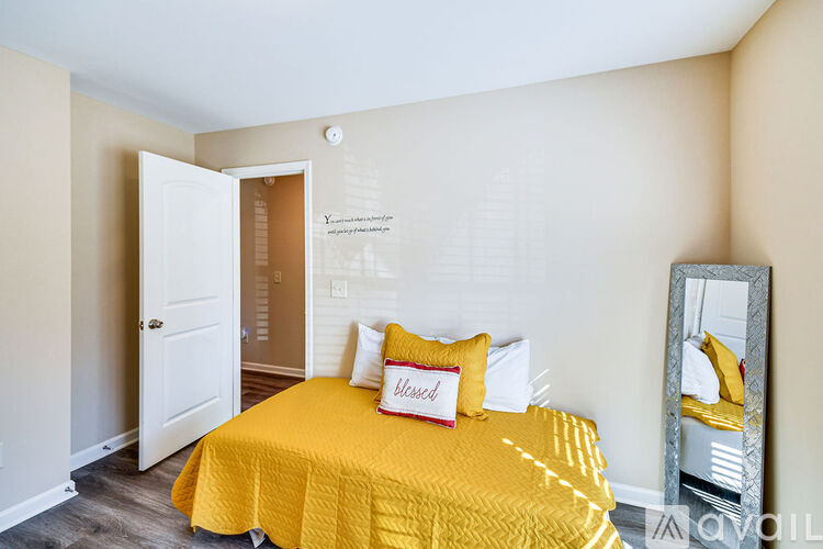 A bedroom with a bed covered in a yellow bedspread and two pillows.