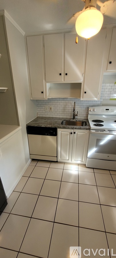 A kitchen with white cabinets and a black dishwasher.