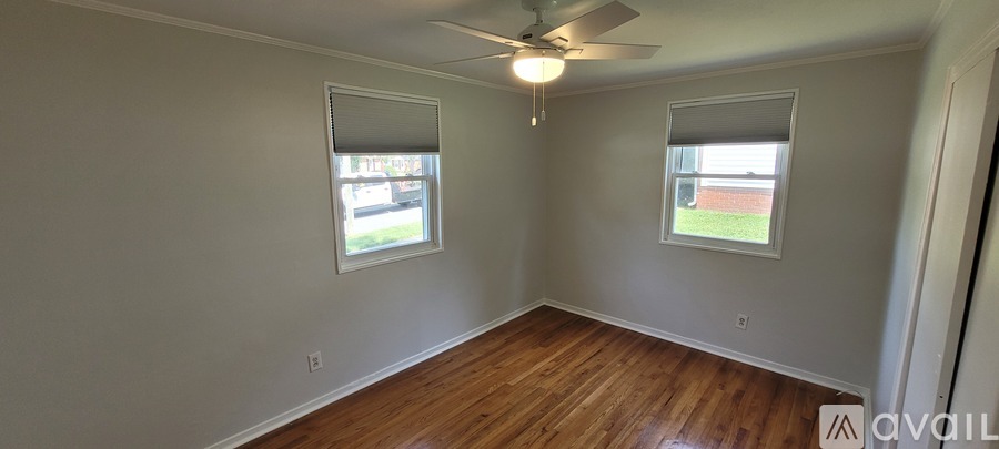 A room with wooden floors and two windows.