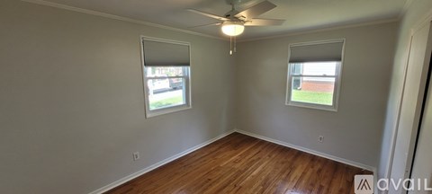 A room with wooden floors and two windows.