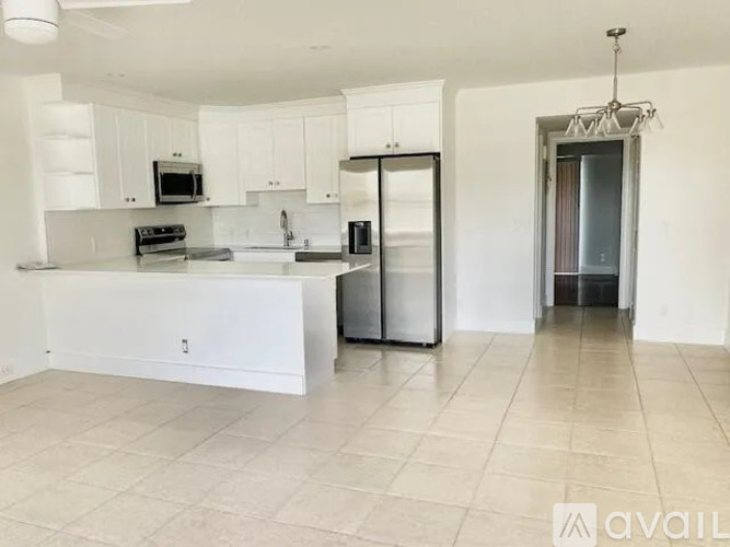 A kitchen with white cabinets and appliances in a spacious room.