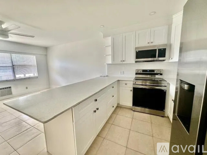 A kitchen with white cabinets and appliances is available for rent.