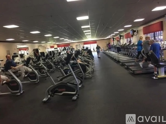 A gym with people exercising and various exercise equipment.