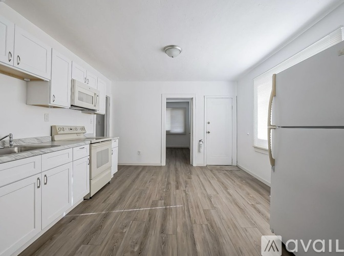 A kitchen with white cabinets and a wooden floor.