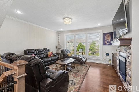 A living room with a black leather couch and a stone fireplace.