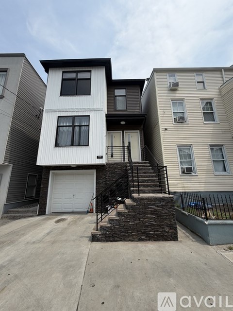 A two-story house with a garage and a staircase leading to the entrance.