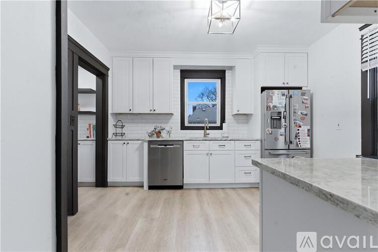 A kitchen with white cabinets and a marble countertop.