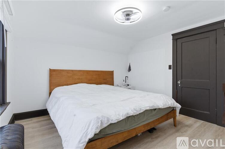 A bedroom with a bed, a ceiling light, and a door.