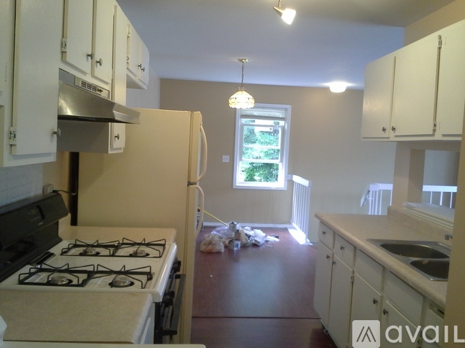 A kitchen with a stove, cabinets, and a window.