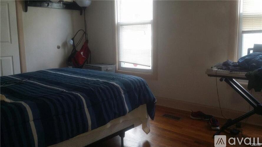 A bedroom with a bed, a desk, and a window.