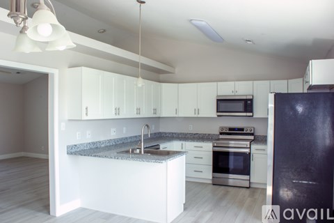 A modern kitchen with white cabinets and a black refrigerator.