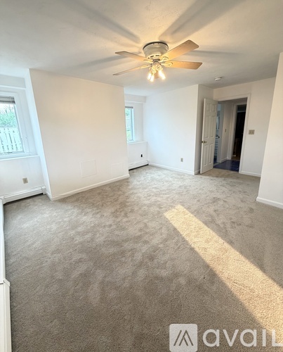 A spacious room with a ceiling fan and carpeted floor.
