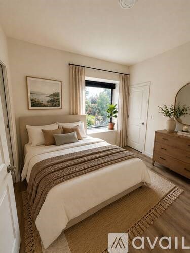 A bedroom with a large bed and a window with curtains.