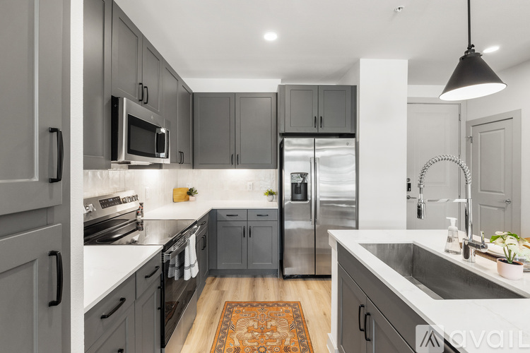 A modern kitchen with dark grey cabinets and stainless steel appliances.