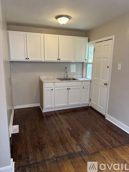 A kitchen with white cabinets and a wooden floor.