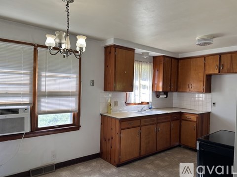 A kitchen with wooden cabinets and a black dishwasher.
