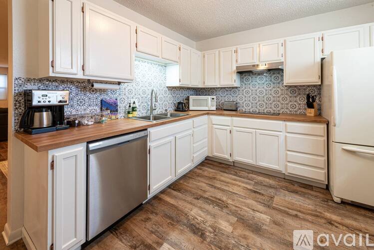 A kitchen with white cabinets and a wooden counter top.