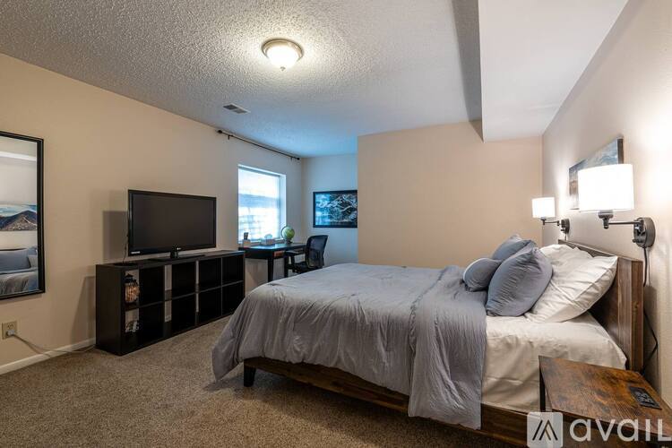A bedroom with a bed, a television, and a window.