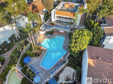 A large swimming pool surrounded by trees and a building in the background.