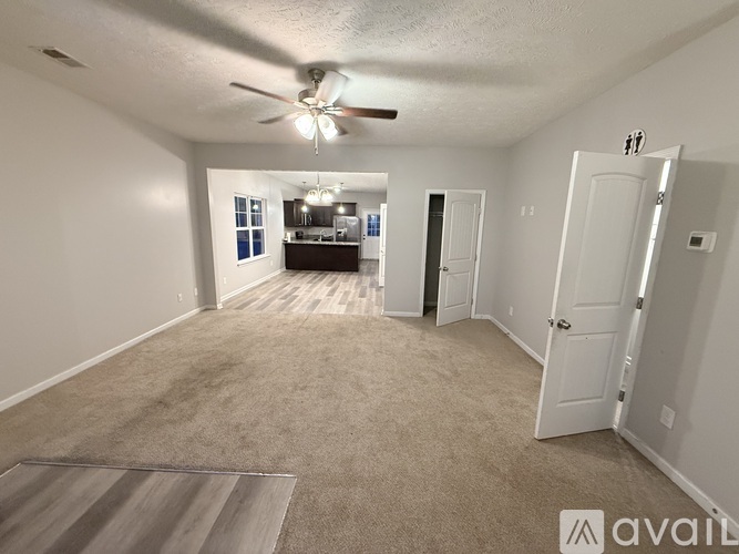 A spacious room with a ceiling fan and carpeted floor.