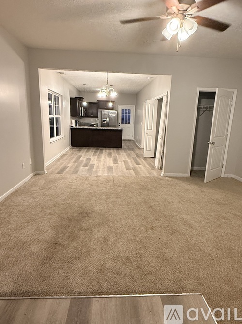 A spacious living room with a carpeted floor and a ceiling fan.