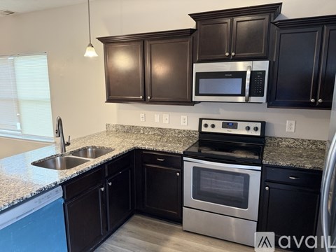 A kitchen with black cabinets and a stainless steel oven.