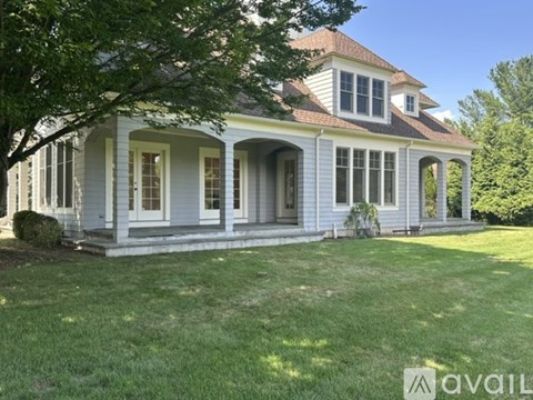 A house with a porch and a tree in front.