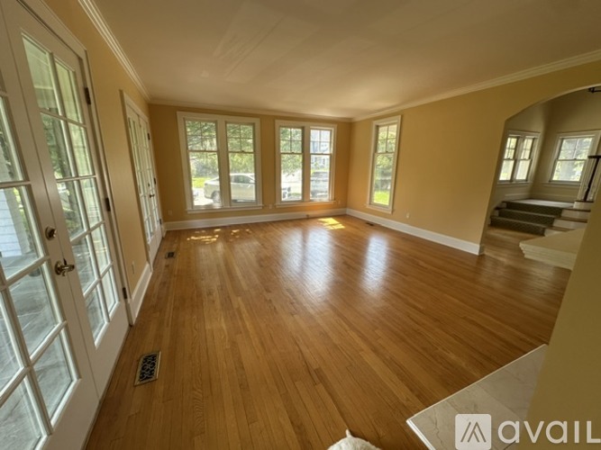 A spacious room with wooden flooring and large windows.