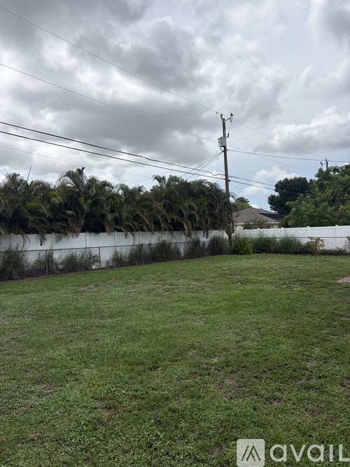 A grassy field with a fence and trees in the background.