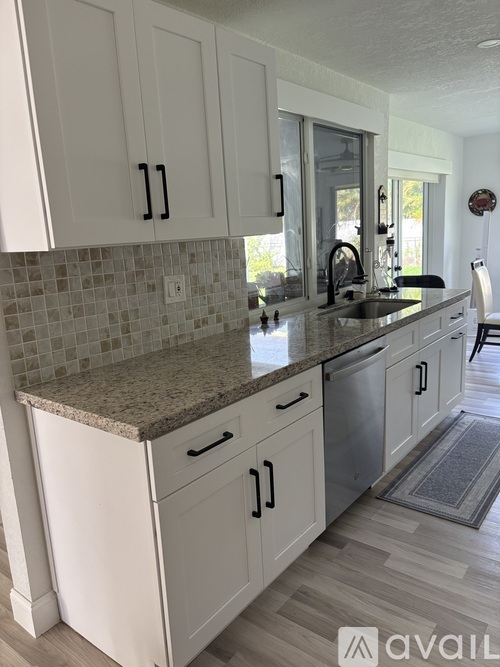 A kitchen with white cabinets and a granite countertop.