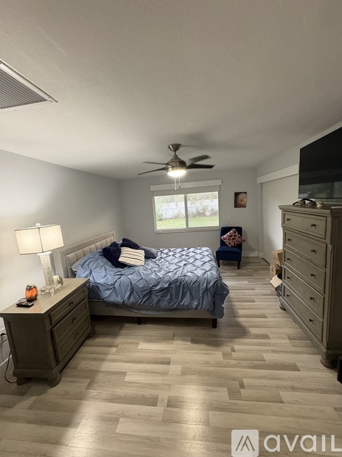 A bedroom with a bed, dresser, and ceiling fan.
