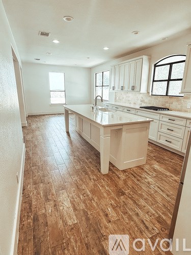 A kitchen with wooden flooring and white cabinets.