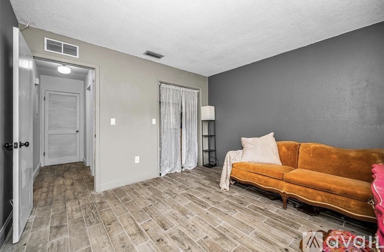 A living room with a brown couch and a door on the left.