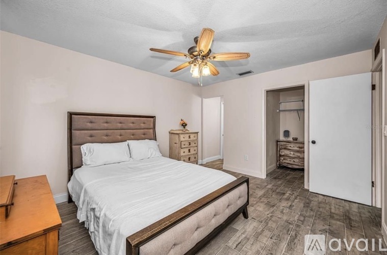 A bedroom with a large bed and a ceiling fan.