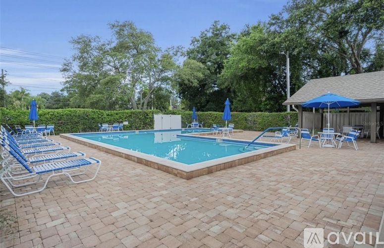 A pool surrounded by a brick patio and blue umbrellas.