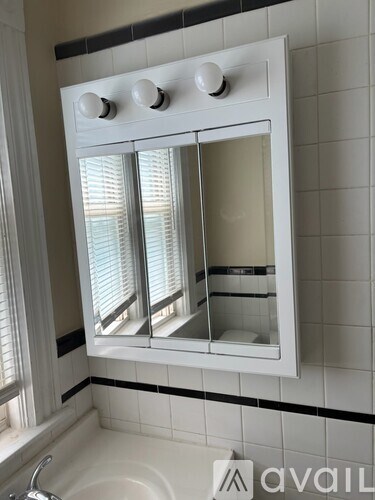 A white medicine cabinet with a mirror and four lights above it.