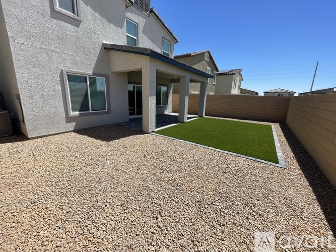 A house with a gravel driveway and a small grassy area in the backyard.