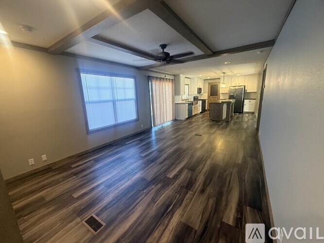 A spacious room with wooden flooring and a ceiling fan.