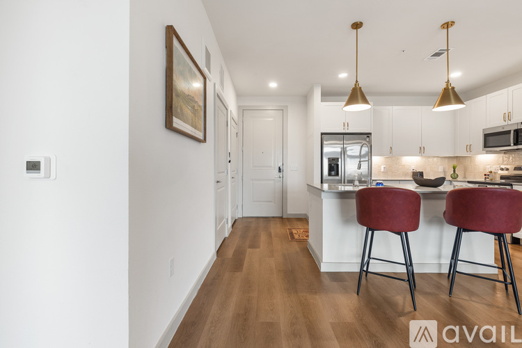 A kitchen with white cabinets and a bar area with two red chairs.