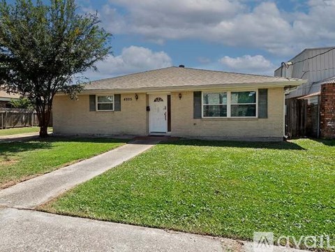 A house with a white door and a tree in front.