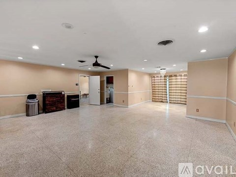 A spacious room with a ceiling fan and a trash bin.
