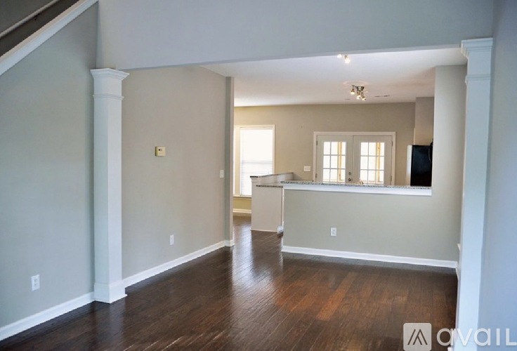 A spacious room with wooden floors and white walls.