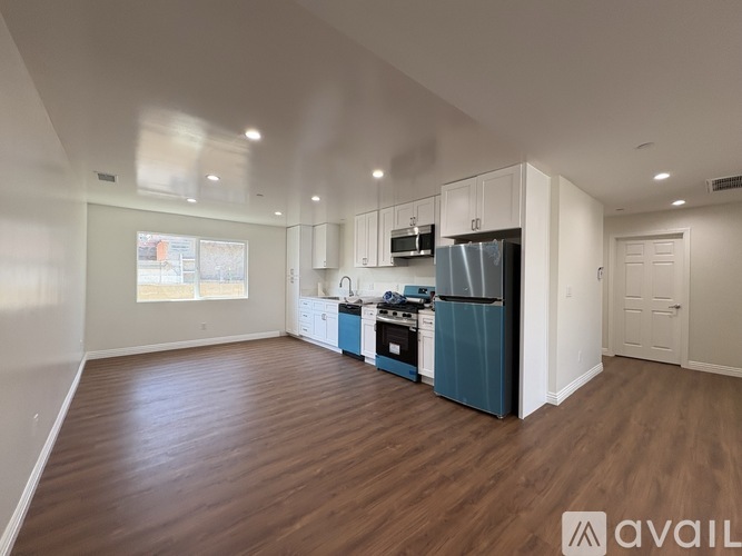A spacious kitchen with white cabinets and a blue refrigerator.