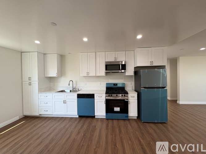 A kitchen with white cabinets and a blue dishwasher.